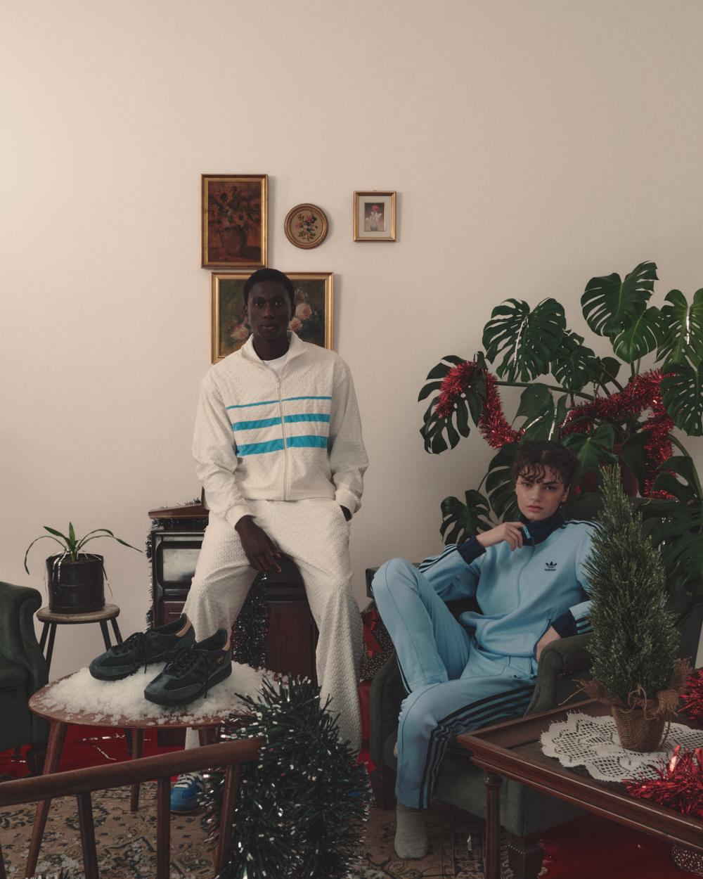 Dos modelos con chándales Adidas en un salón clásico, en formato vertical