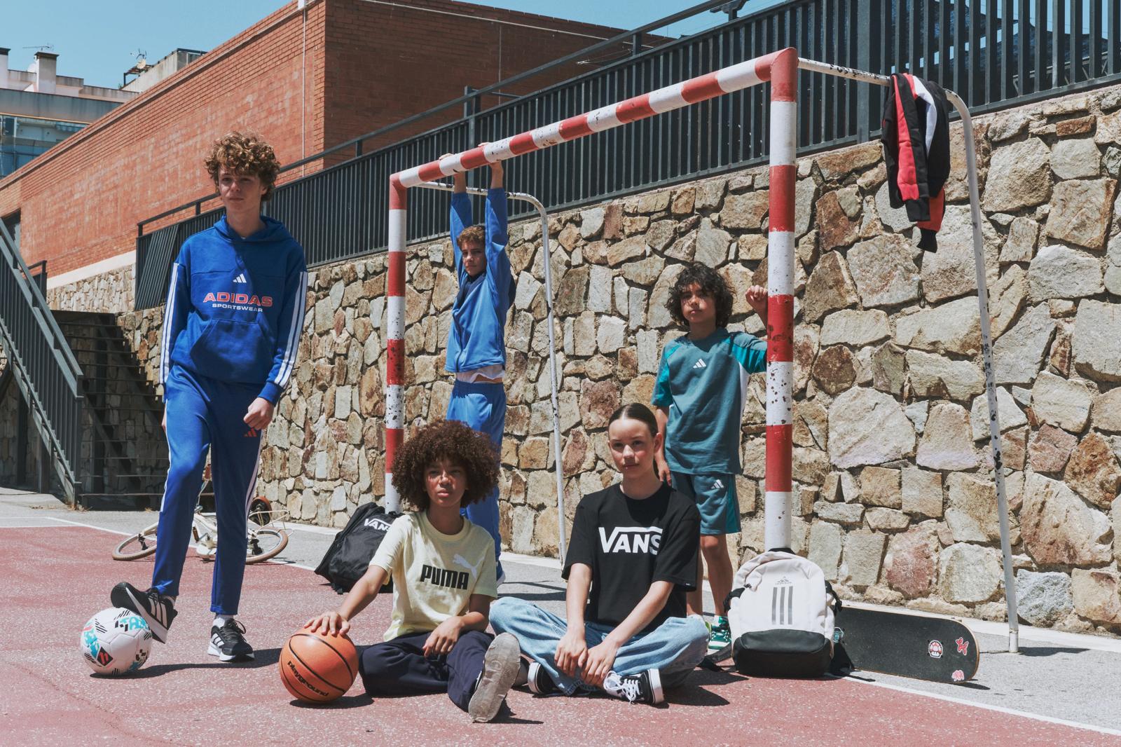Niños con ropa deportiva en el patio del colegio, junto a una portería