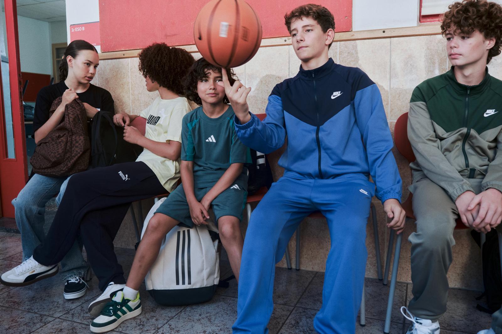Un grupo de escolares sentados en un banco; uno hace girar un balón de baloncesto