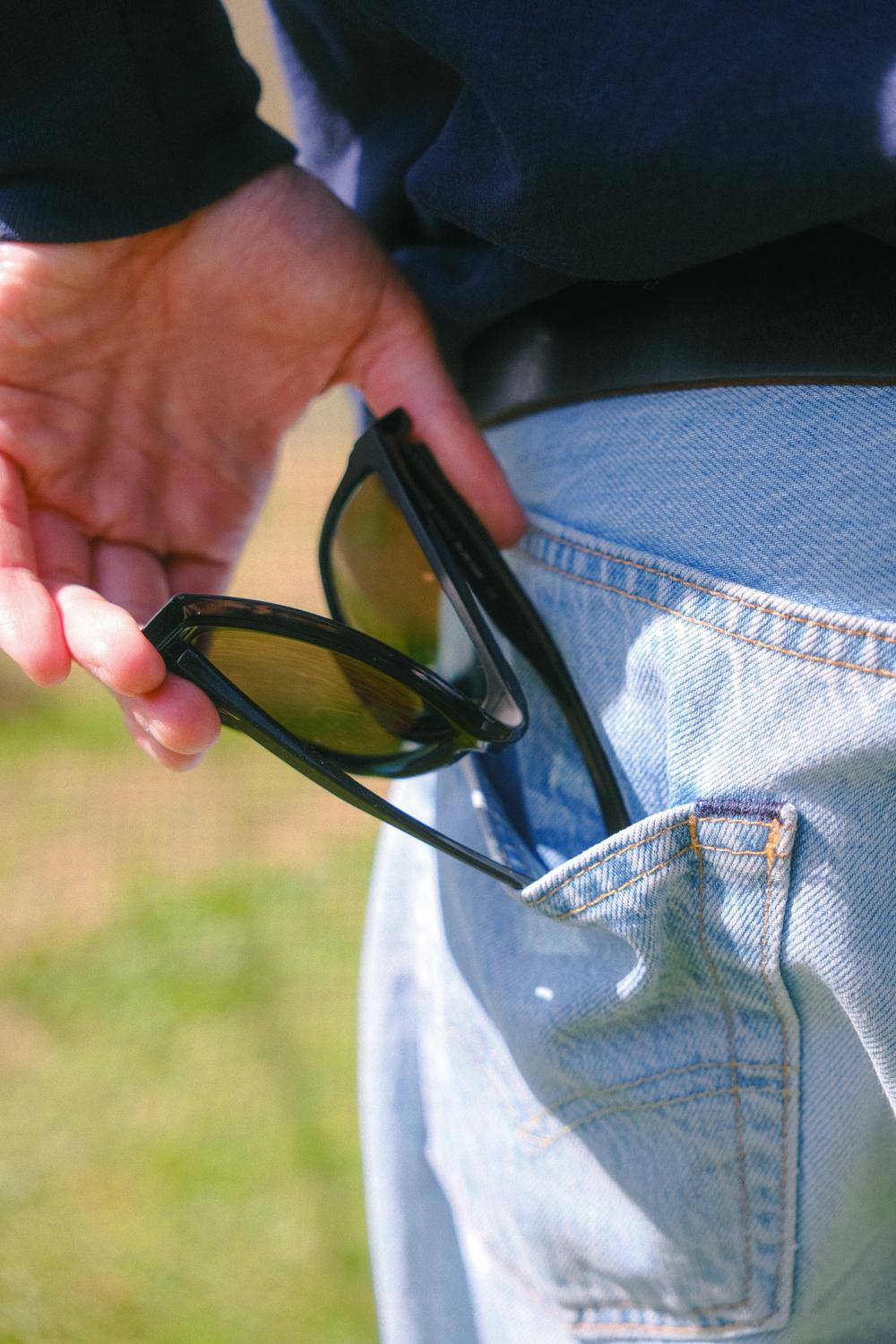 Unas gafas de sol guardadas en el bolsillo trasero de unos vaqueros