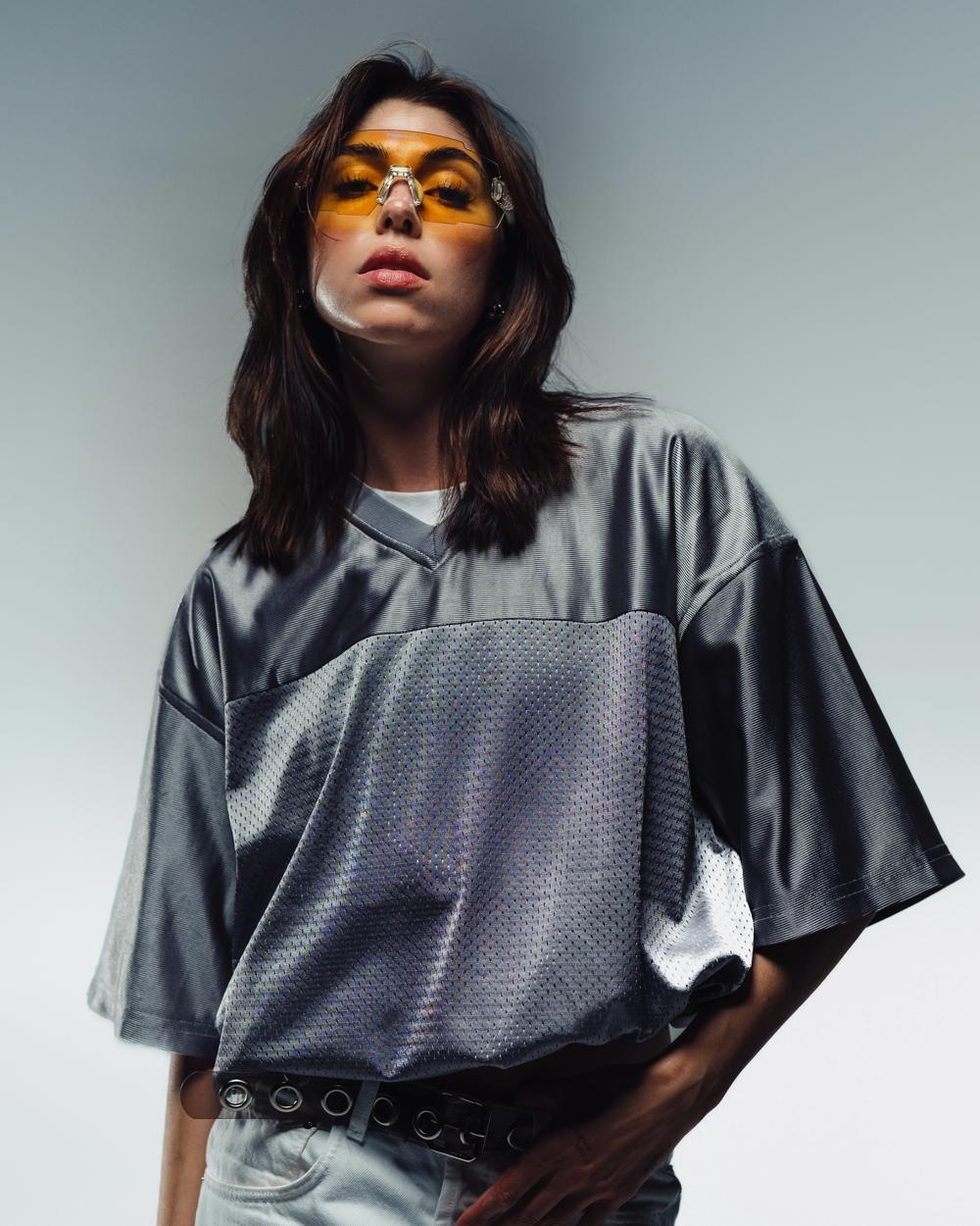 Modelo con gafas de lentes naranjas y camiseta gris satinada